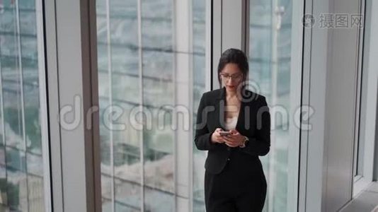 一位年轻的现代商务女性在玻璃和金属建筑背景下的肖像。视频