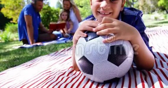 微笑的男孩在公园4k野餐时靠在足球上视频