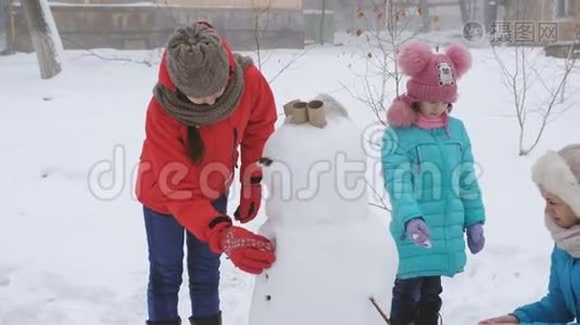 户外冬季家庭游戏。 妈妈和两个女儿一起塑造了雪人。视频