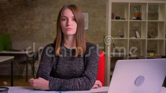 严肃的女孩肖像，坐在办公室的笔记本电脑前视频