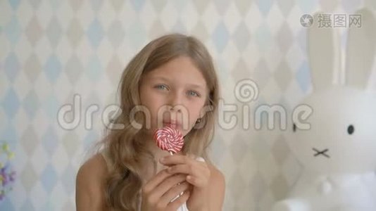 漂亮的小女孩带着棒棒糖，快乐的小女孩在家吃糖果视频