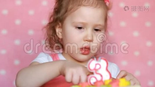 一个有趣的小女孩吃了一个美味的蛋糕来纪念他的生日三年。 一个孩子在一张粉红色的桌子上吃甜点视频