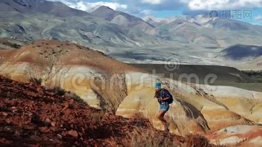 年轻的旅游妇女带着背包和帽子爬上红石山。 那里风景不真实，多云视频