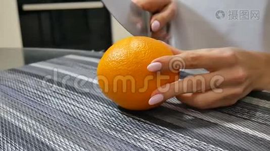 年轻的女性手在家厨房的桌子上切割成熟多汁的橘子视频