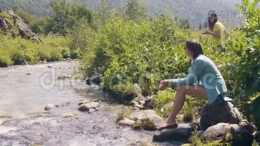 年轻女子坐在河岸上，夏天休息视频