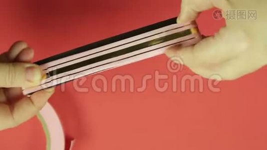 女性手空白粉红色丝带制作礼品弓与模板。 红色背景视频
