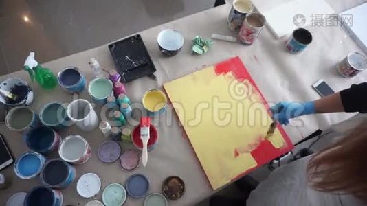 艺术家画了一块木板. 红色和黄色油漆。 艺术工作室。 油漆罐和刷子视频