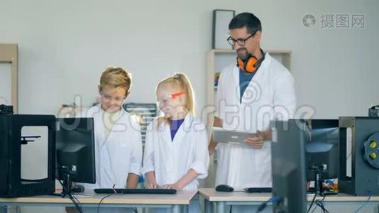 一个十几岁的男孩和一个女孩正和一个研究人员一起看着一台电脑显示器视频