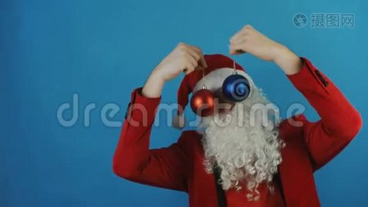 新年，男人就像一个圣诞老人，带着蓝色背景的红色和蓝色圣诞球玩具视频