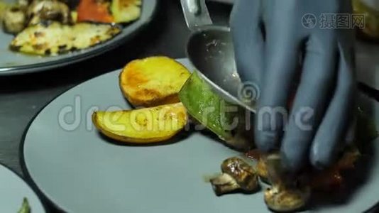 黑手套厨师形成一盘现成的烤菜，把它们铺在盘子里，热蔬菜烤架上视频