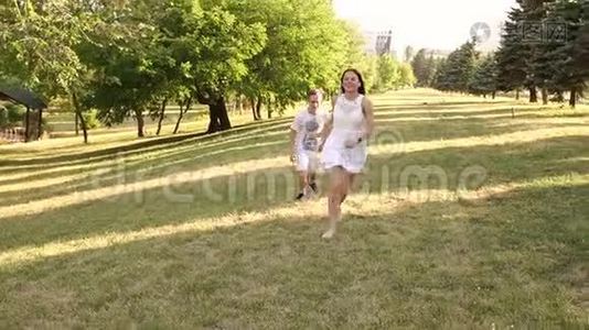 快乐的年轻夫妇在公园的草地上奔跑。 慢动作。视频