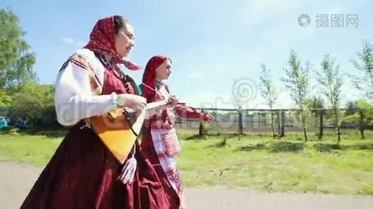 两个穿着俄罗斯传统服装的年轻妇女在村里的道路上行走视频