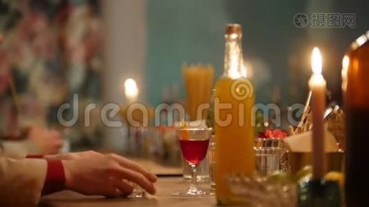 专业的酒保在酒吧里用柔和的室内灯光将橙色饮料倒入一个小玻璃杯中视频
