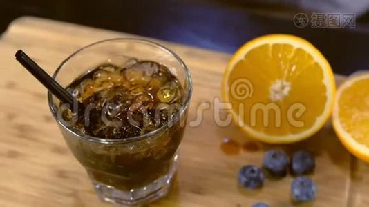 酒保用蓝莓和橘子的香味在岩石玻璃上装饰鸡尾酒。手特写。视频