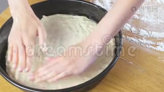 女人`手把酵母面团放在圆形烤片上。 做披萨。视频