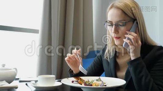 年轻的金发女经理打电话在咖啡馆吃饭。视频
