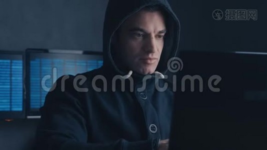 网络犯罪概念。 一个被通缉的黑客在黑暗的办公室里用电脑视频