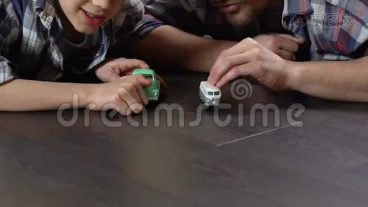 男孩和父亲在家里的地板上赛车比赛，玩游戏视频