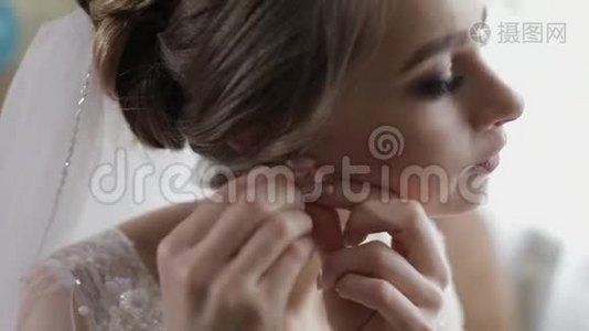 优雅的金发新娘戴着漂亮的耳环。 婚礼当天早上的女人视频