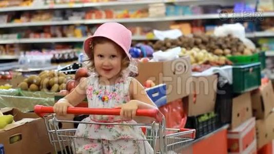 商店折扣。 出售。 超市里的小女孩坐在购物车里。视频