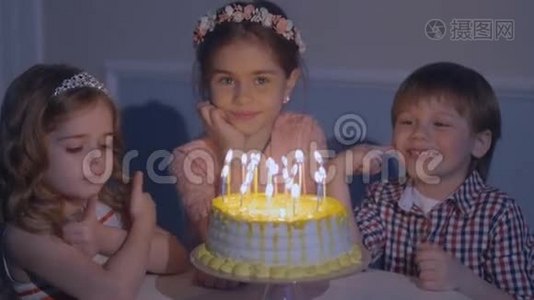 小孩子拿着蛋糕坐在红桌旁。 生日聚会上的孩子们快乐。视频