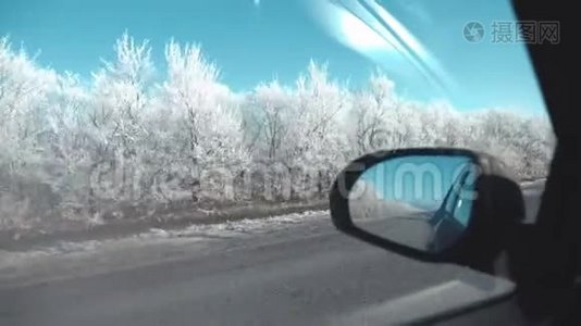 从车窗上看到的景色，白雪覆盖的道路和霜冻的树木，一个美丽的冬日。视频