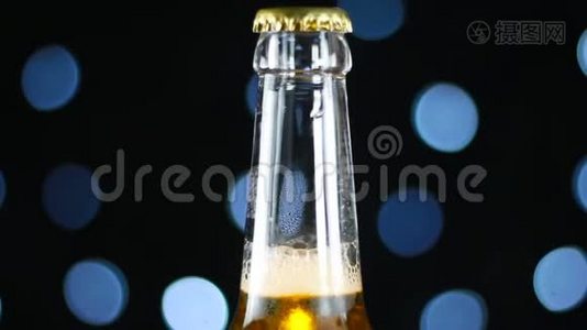 淡啤酒放在清澈的瓶子里，在黑色背景上旋转，明亮的灯光下视频