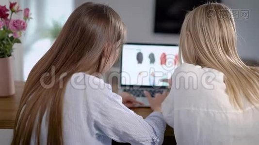 两个年轻的女性朋友正坐在家里，在网上购物，他们使用带wifi的现代笔记本电脑视频