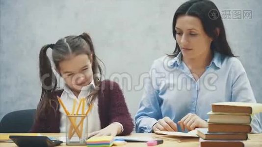 坐在桌子旁的漂亮女学生。 在家和她妈妈做作业。视频
