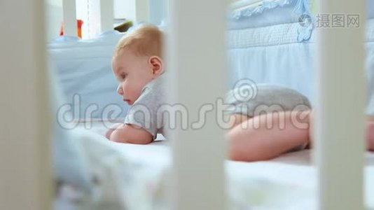 一个小孩在婴儿床上的特写镜头，笑着从婴儿床的格子间侧视。 快乐的童年，幼稚的快乐视频