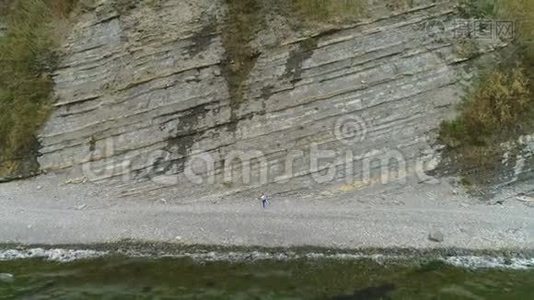 女人正在做瑜伽和身体锻炼的腿在岩石背景。 空中美丽的画面。视频