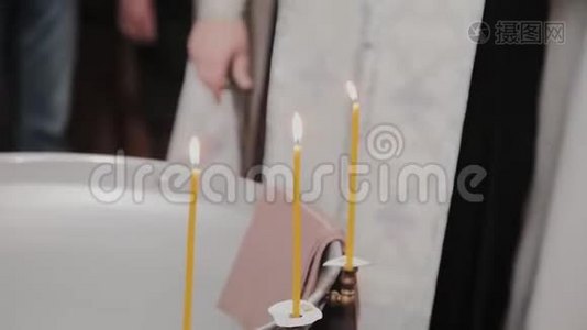 在东正教教堂用燃烧的蜡烛洗礼婴儿的字体。视频