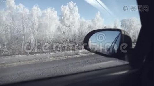 从车窗上看到的景色，白雪覆盖的道路和霜冻的树木，一个美丽的冬日。视频