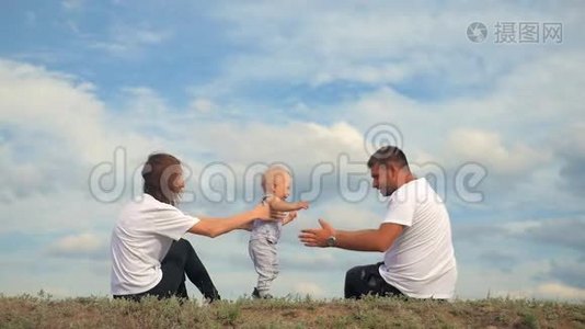幸福的一家人坐在绿草上。 家庭在户外玩得很开心。 快乐的年轻家庭在一起视频