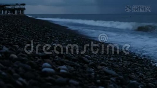 暴风雨中的海浪拍打着大海上的鹅卵石，背景是雨云视频