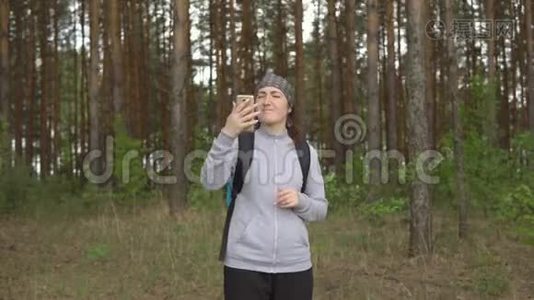 在森林里试图捕捉移动信号的年轻女子视频