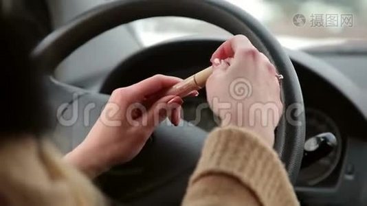女孩打开口红坐在汽车的车轮后面。视频