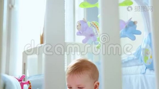 一个小孩在婴儿床上的特写镜头，笑着从婴儿床的格子间侧视。 快乐的童年，幼稚的快乐视频