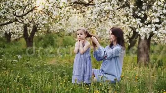 可爱的年轻母亲和她的女儿在盛开的苹果花园里视频