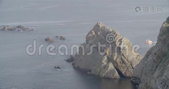 一艘船在右侧航行，在海附近形成一个巨大的岩石群视频