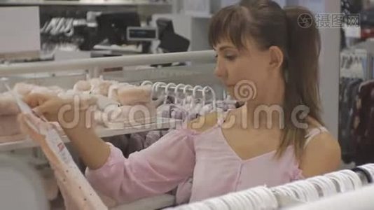 宝贝服装店里漂亮的女人。 白种人女性选择婴儿服装的特写。视频
