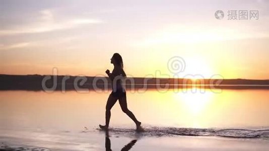 有长发的苗条女人在户外跑步。 在水边慢跑。 海边。 太阳照耀着背景视频