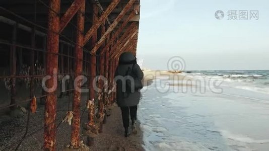 女孩走在海边，靠近金属生锈的建筑视频