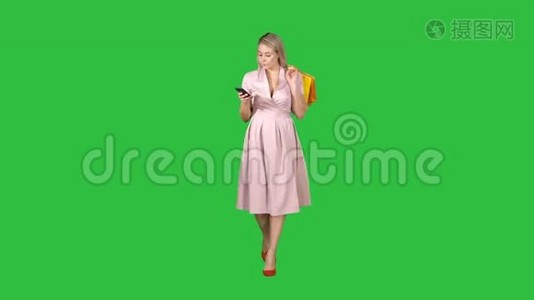 购物妇女带着袋子在智能手机上发短信，而走在绿色屏幕上，Chroma键。视频