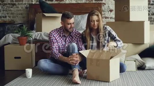 这对年轻夫妇很兴奋，他们正在整理东西，打开盒子，拿个人物品，搬到新公寓后交谈视频