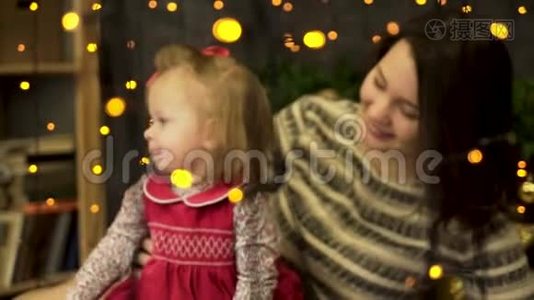 年轻的，迷人的，微笑的女人妈妈带着一个快乐的，甜美的孩子在黄色后面的美丽的新年工作室里视频