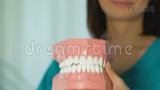 牙医展示下颚模型，提供正确牙齿和口腔护理的课程视频