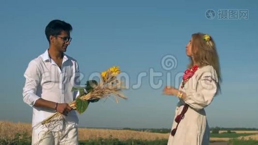 慢动作，印度男子在片中给成年妇女一束麦穗和向日葵旁边的麦田视频