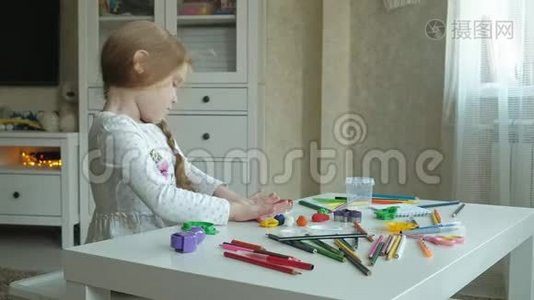 一个小女孩玩橡皮泥，用手把它卷起来，在上面剪一个图形、图形和彩色铅笔视频