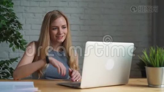 年轻的女商人坐在办公室里，手提电脑和视频聊天。 专业女性通过电脑聊天视频